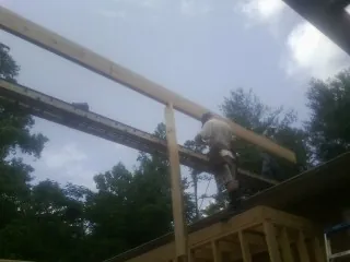 Carpenter setting a ridge beam over a new addition frame — Ice Dam Removal by Roofing Brothers in Independence
